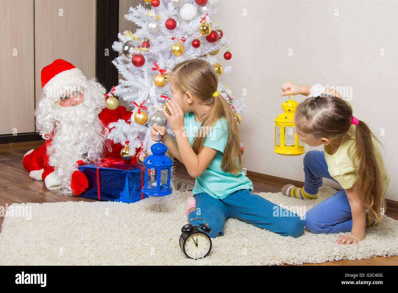 Two girls with flashlights to see Santa Claus who was trying to discreetly put the presents under the Christmas tree Stock Photo