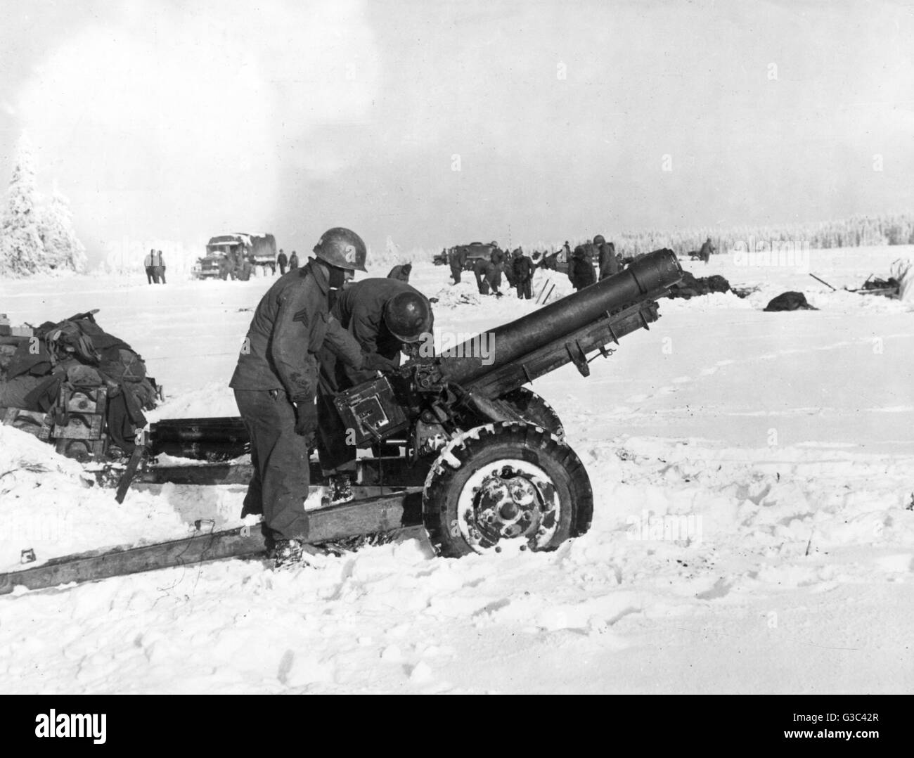 American soldiers of the 84th Division, 1st U.S.Army, set upM3 105mm howitzers in the snow near Odeigne, Belgium on the northern flank of the German salient in the Ardennes, during the Battle of the Bulge.     Date: December 1944 Stock Photo