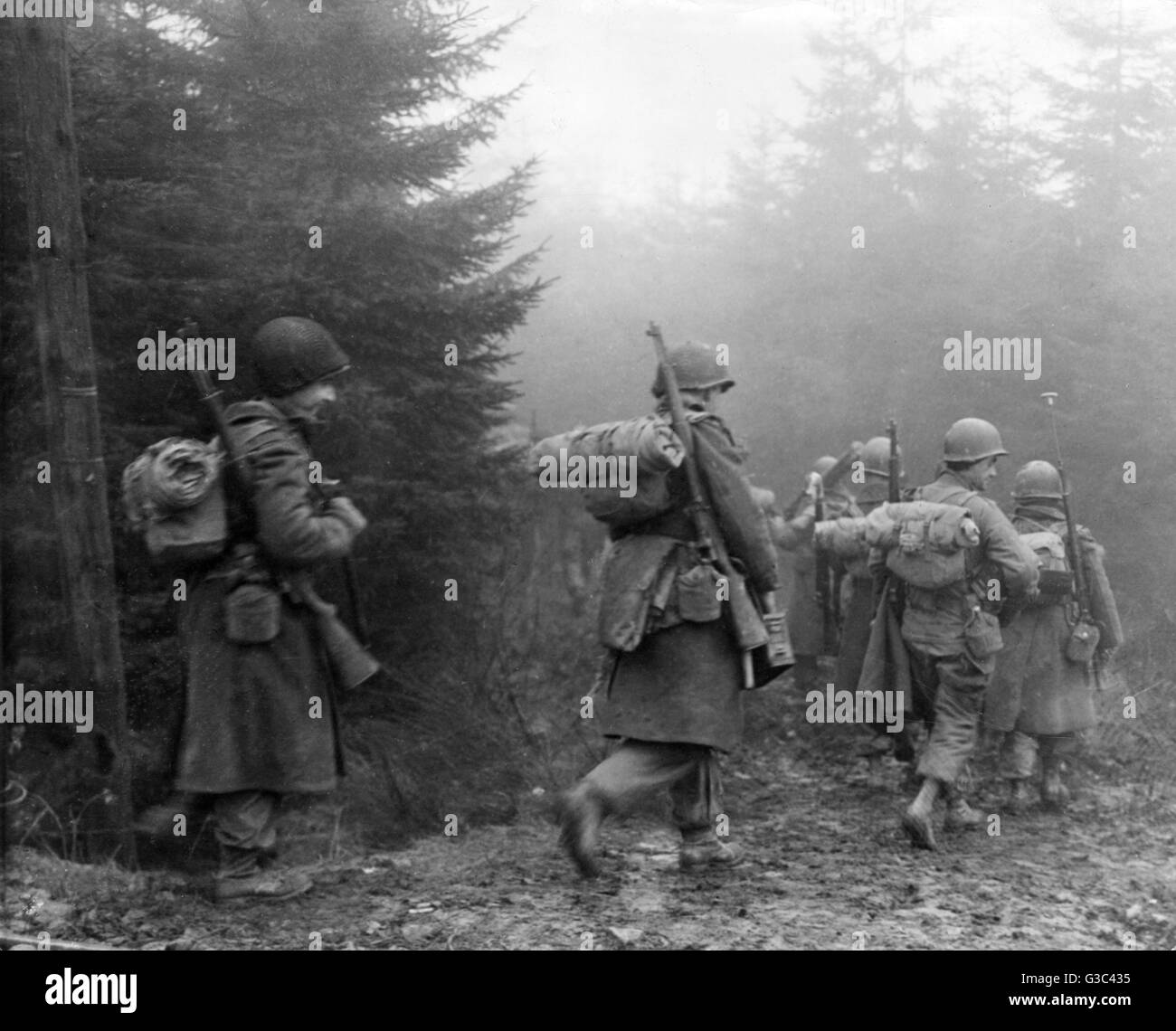 American soldiers advance through the forest of Ardennes, on their way to relieve the besieged town of Bastogne which had been surrounded during the German counter-offensive which became known as the Battle of the Bulge.     Date: December 1944 Stock Photo