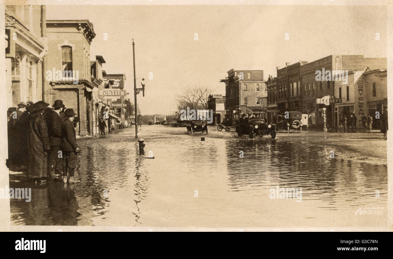 Flooding in the street in Norfolk, Nebraska, USA, March 1917, with people and cars coping as