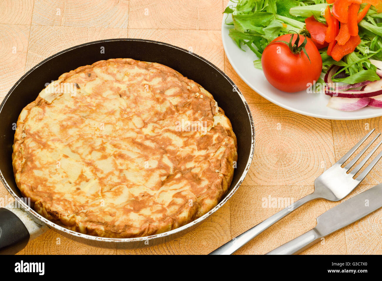 A Spanish omelette or tortilla served with a tomato and green salad Stock Photo