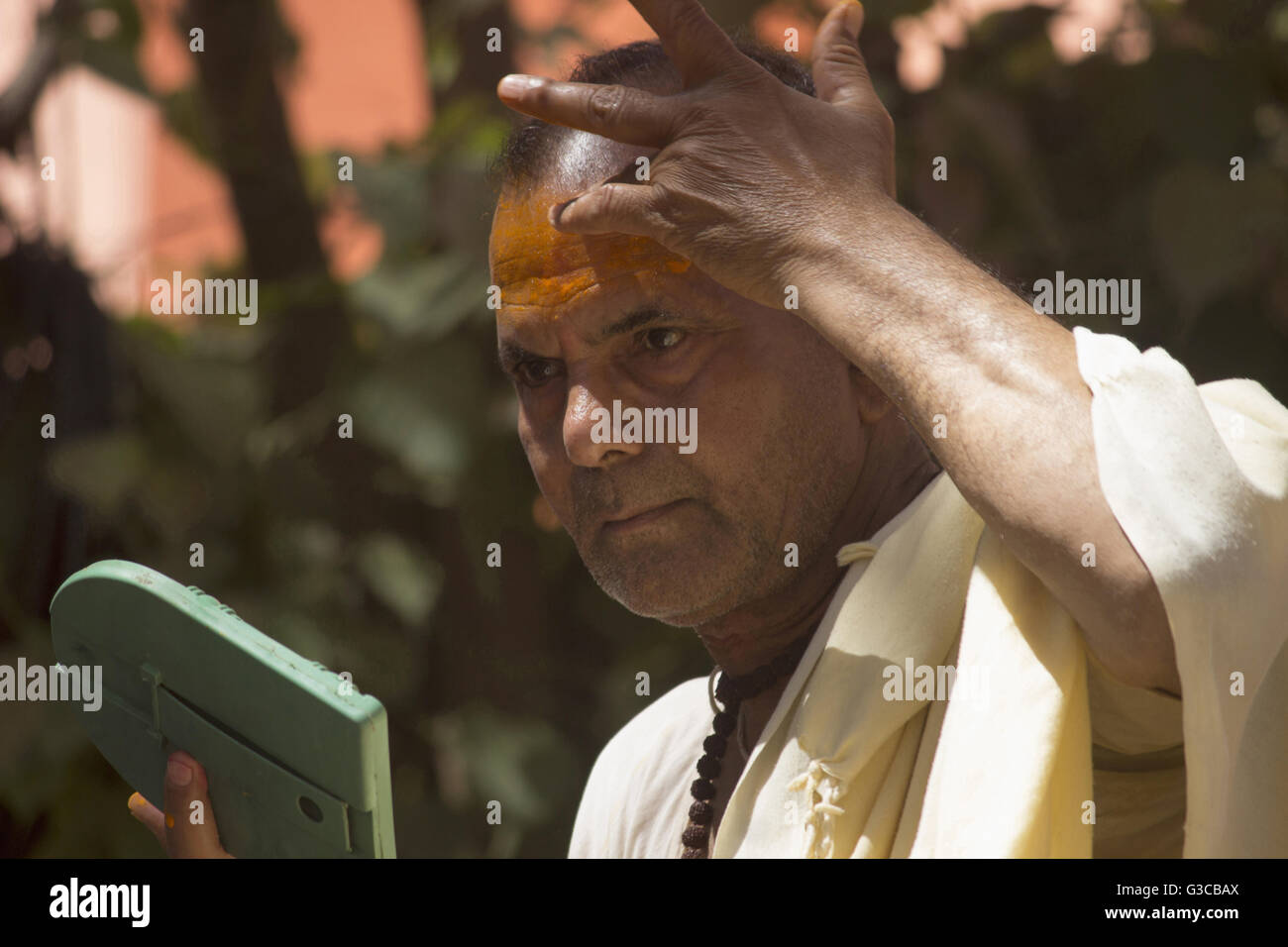 Priest applying sandalwood paste on his forehead. Kumbh Mela 2016. Ujjain, Madhya Pradesh, India Stock Photo