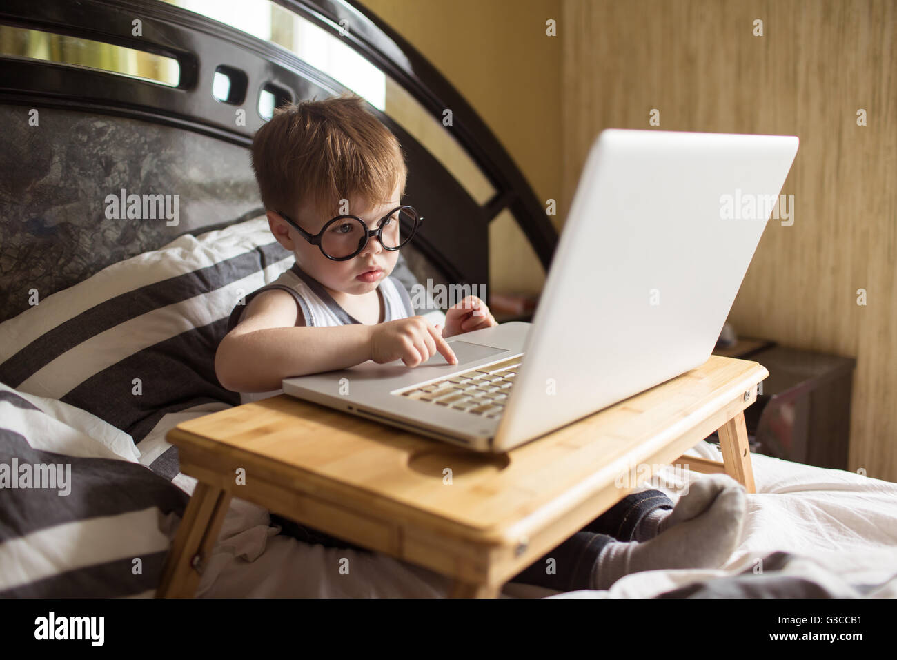 Toddler boy laying on the bed with laptop Stock Photo - Alamy