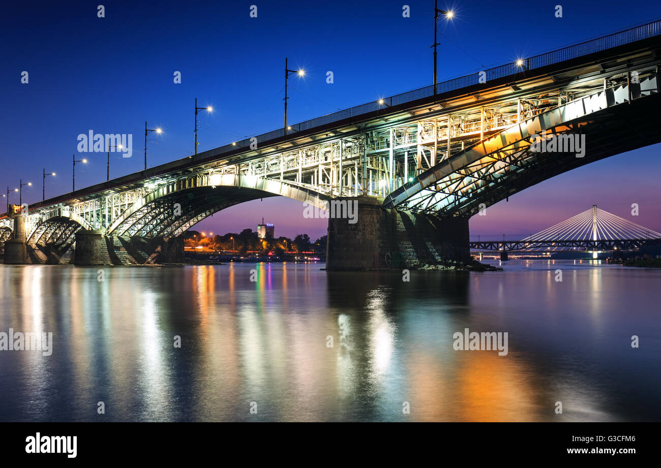 Backlit bridge at night and reflected in the water.Poniatowski Bridge Stock Photo