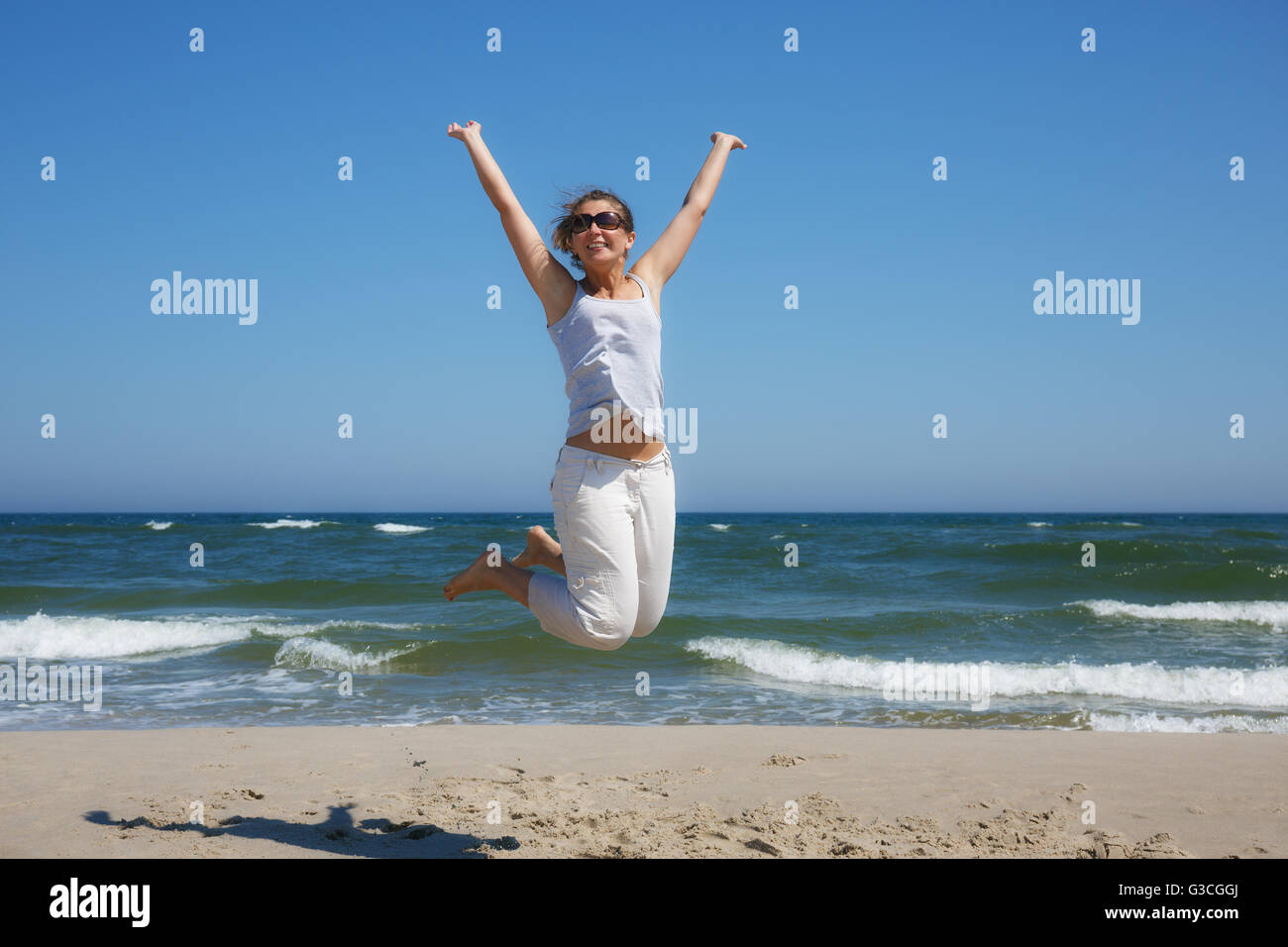 Woman in a jump shot on the beach of the Baltic sea in summer Stock Photo