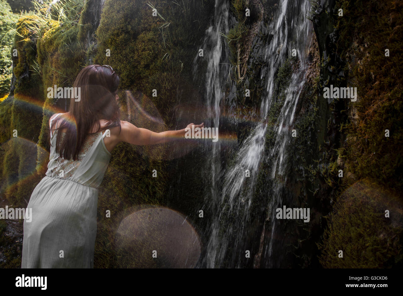 Waterfall Weißenbronnen, girl holding hand in the water, district Ravensburg, Baden-Württemberg, Germany, moss, water, light reflections, Stock Photo