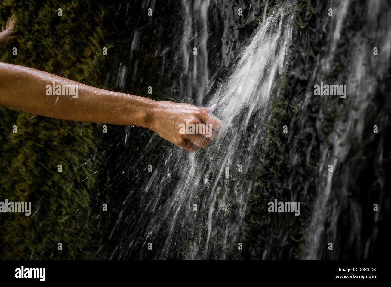 Waterfall Weißenbronnen, girl holding hand in the water, district Ravensburg, Baden-Württemberg, Germany, moss, water, light reflections, Stock Photo