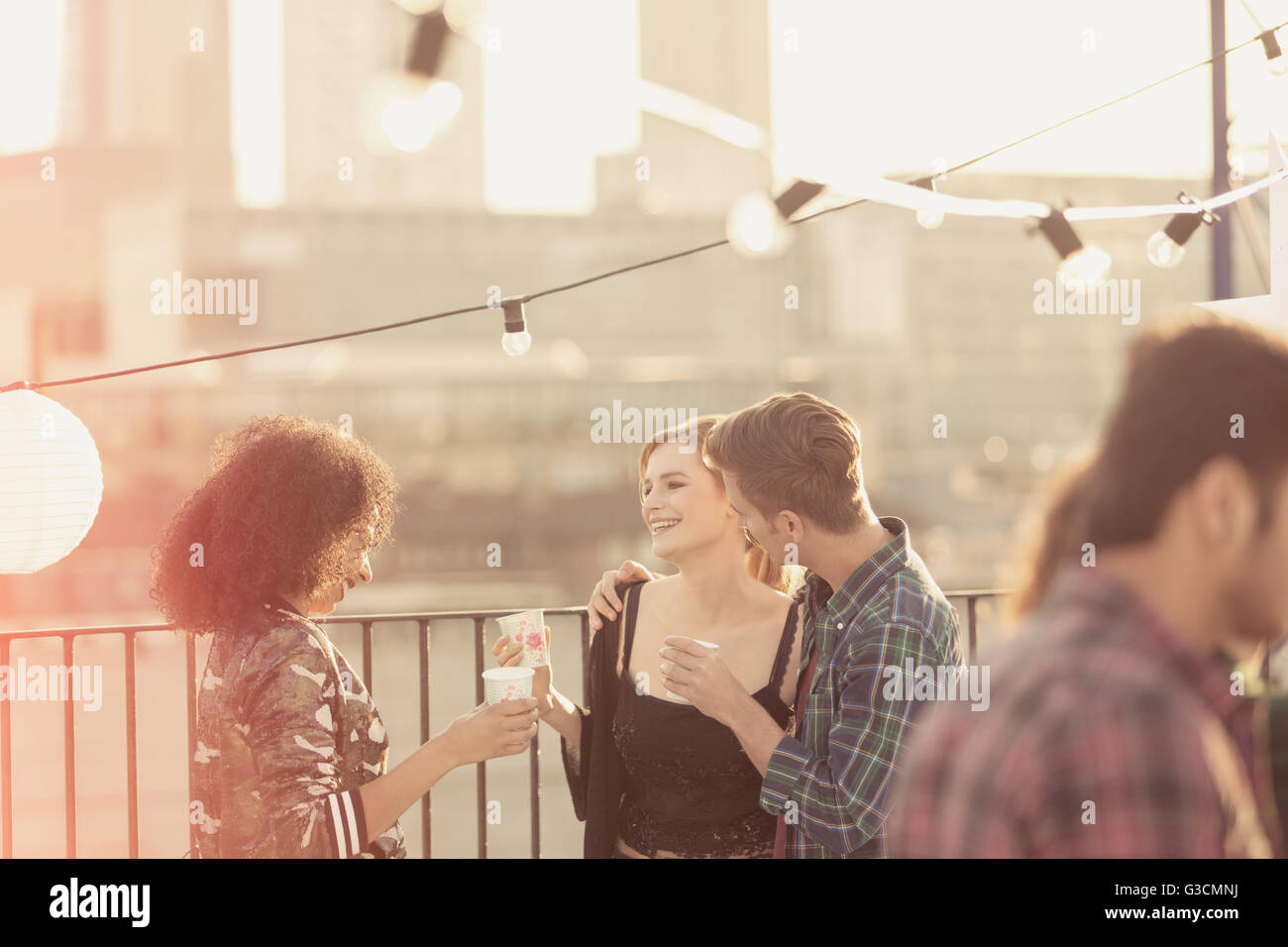 Young adult friends talking and drinking at rooftop party Stock Photo