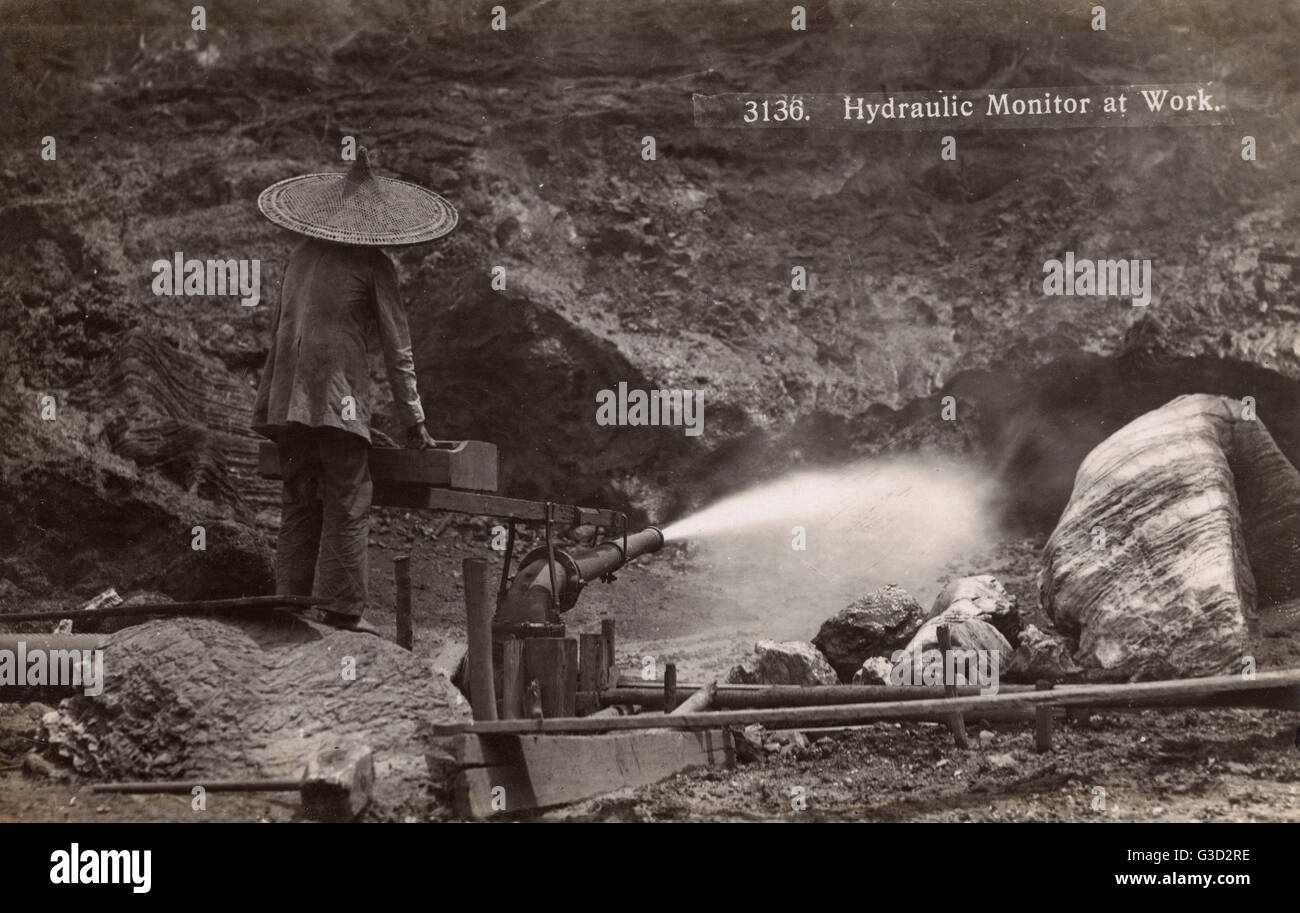 China - Using high-pressure water jet in mining operation.     Date: circa 1930s Stock Photo
