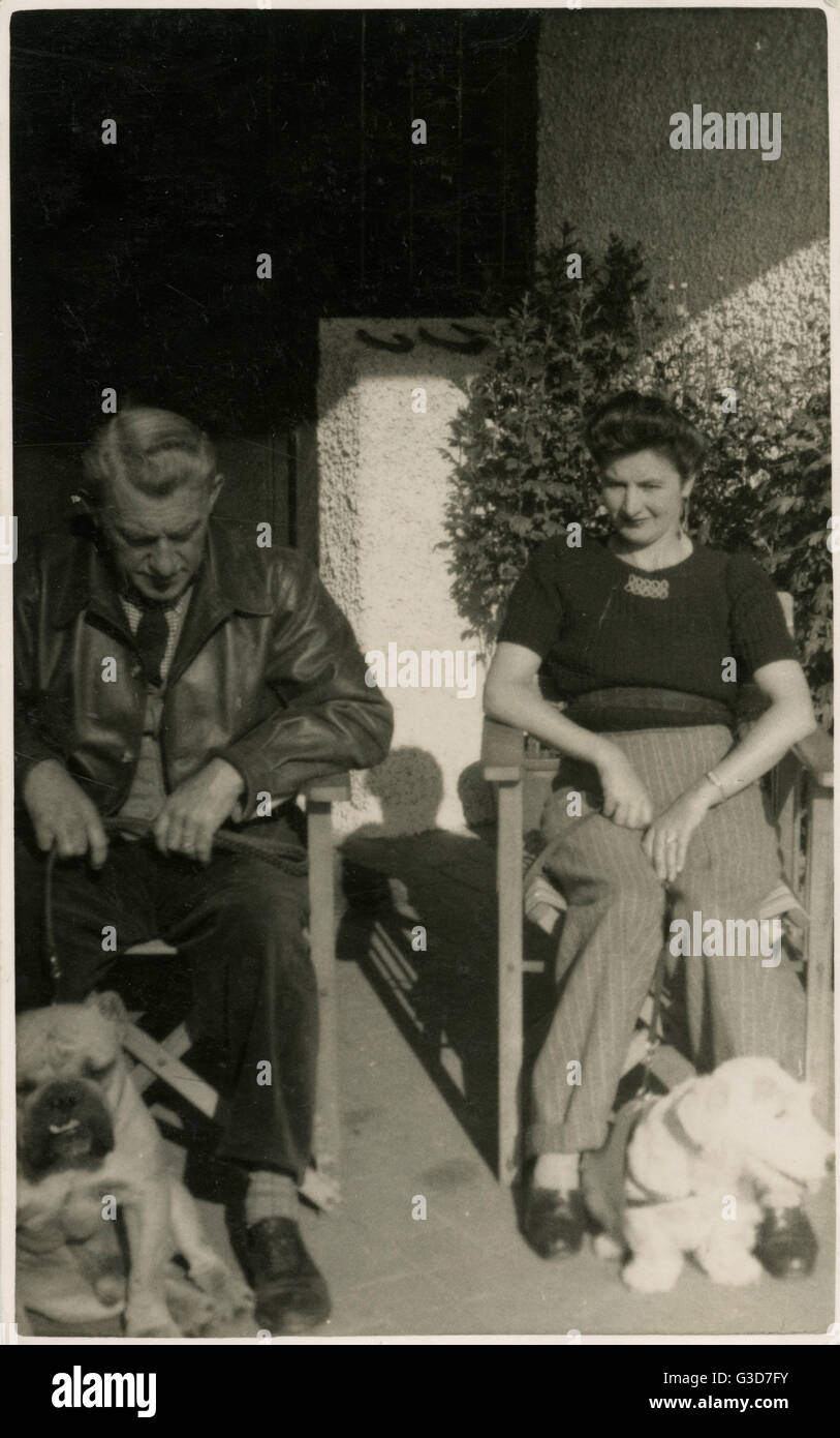 Couple in garden chairs with two dogs Stock Photo - Alamy