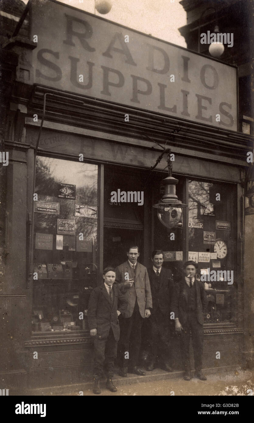 Radio supplies and electrical shop, late 1920s, in an unknown location in  Britain. Advertising for Burndept and Amplion radios in the window. Four  male staff stand in the doorway, one of them