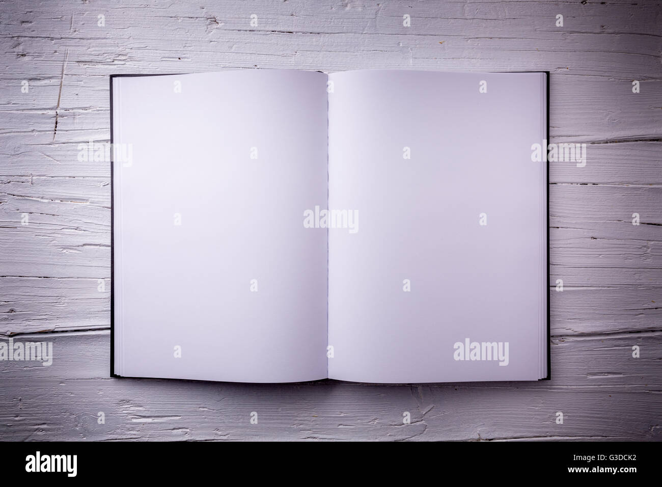 Open blank textbook on white wooden weathered background. Top-view, closeup. Stock Photo