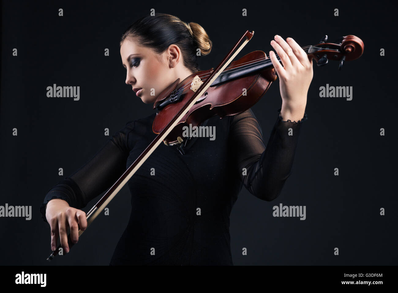 Beautiful young woman playing violin over black background Stock Photo ...