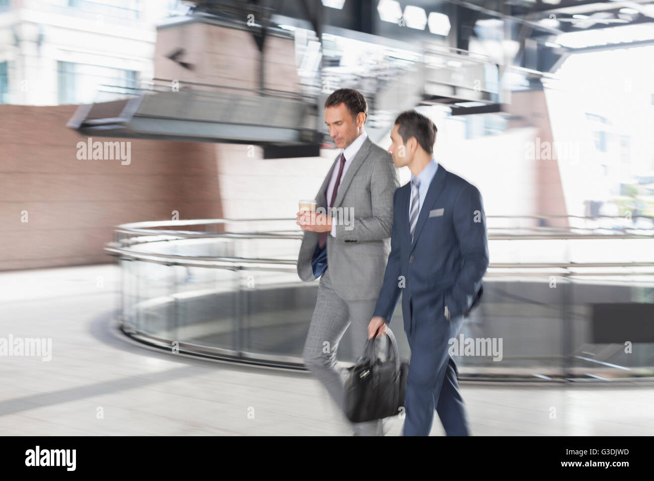 Corporate businessmen with coffee walking and talking Stock Photo