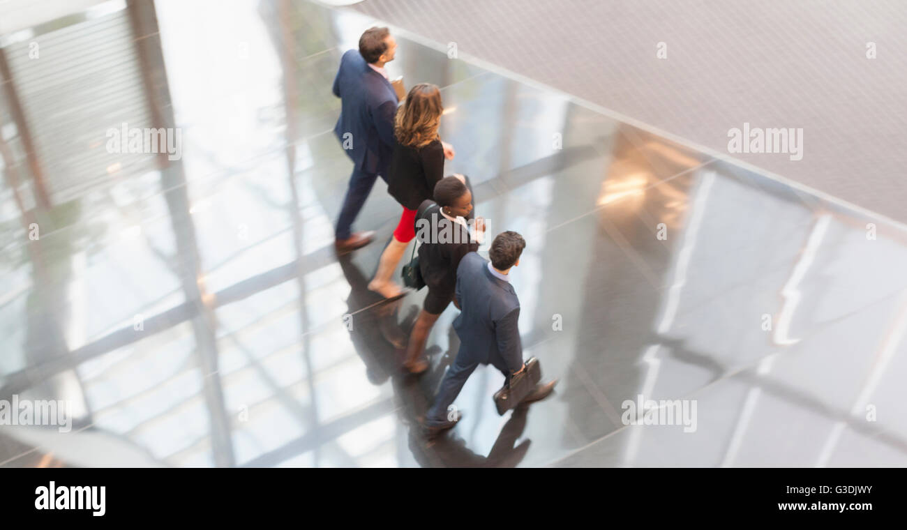 Corporate business people walking in a row in modern office lobby Stock Photo