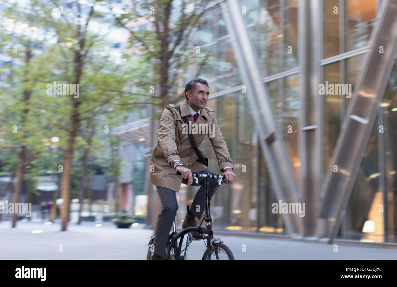 Corporate businessman riding bicycle outside modern building Stock Photo