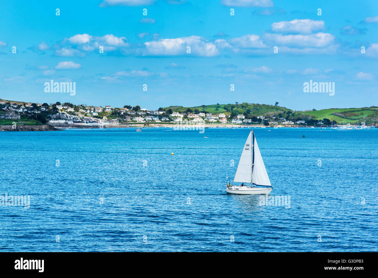 Yacht on the Carrick Roads.  Seen from Pendennis Point, Falmouth with St Mawes in the background. Stock Photo