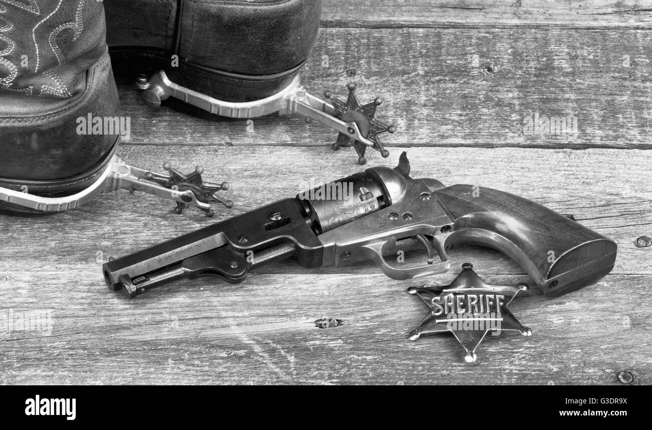 Old western pistol, badge, spurs and cowboy boots in black and white. Stock Photo