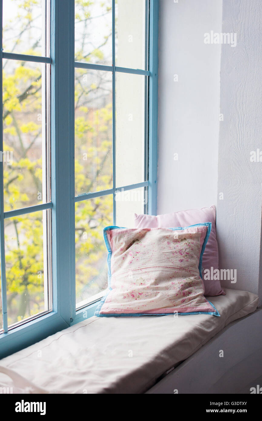 Two pillows airing on window sill in room Stock Photo
