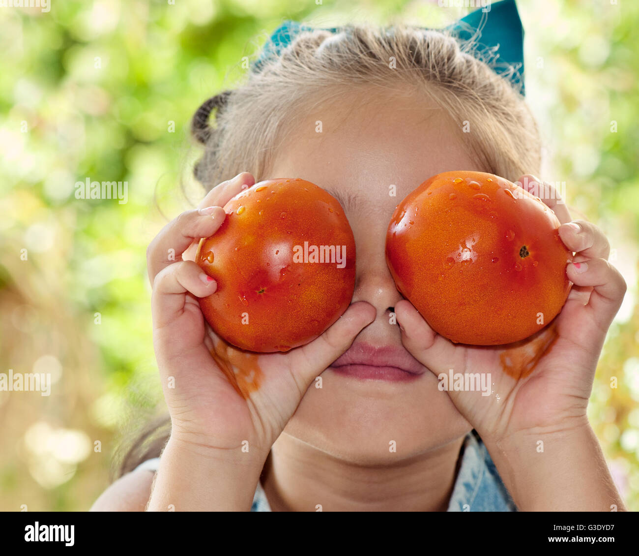 A girl holding two tomatoes in front of her eyes Stock Photo - Alamy