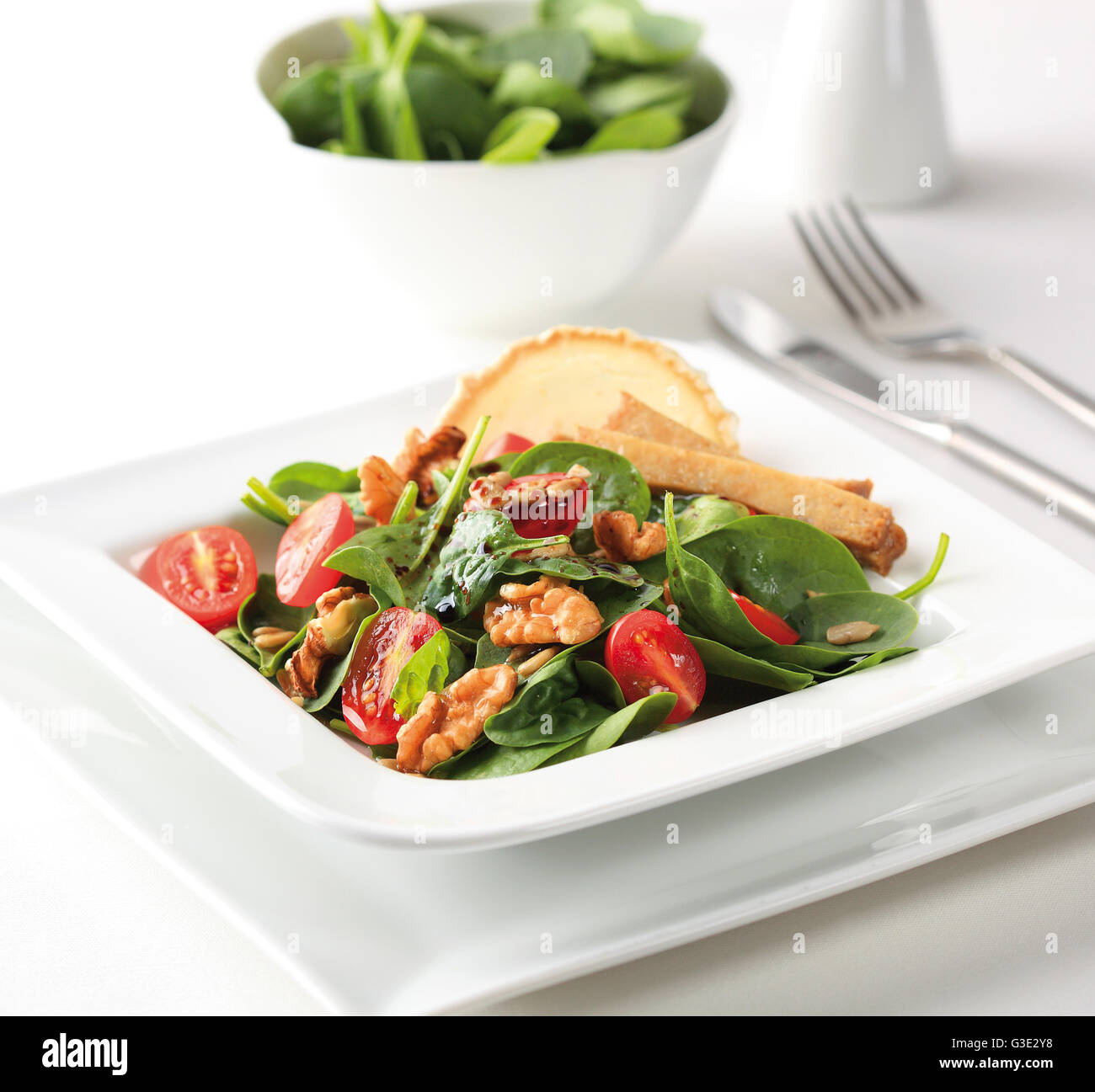 A spinach salad with cherry tomatoes, walnuts, goat cheese and balsamic vinegar. Stock Photo