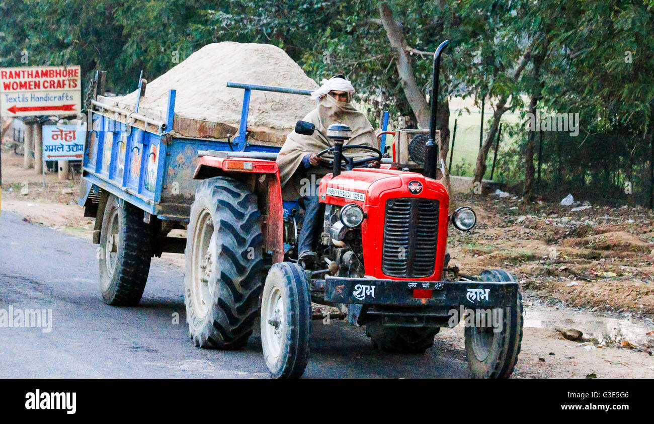 Man driving a red tractor towing trailer India Stock Photo Alamy