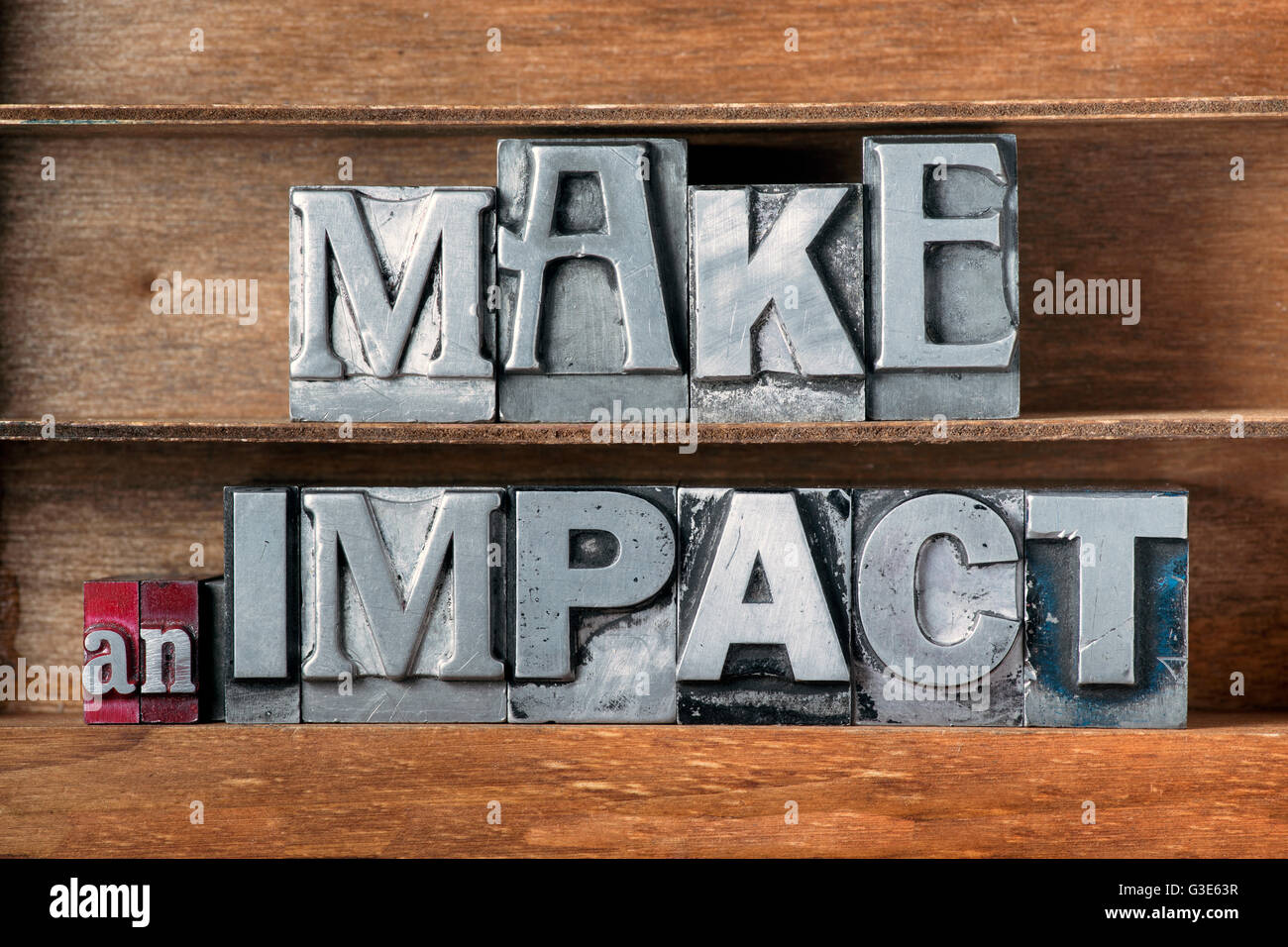 make an impact phrase made from metallic letterpress type on wooden tray Stock Photo