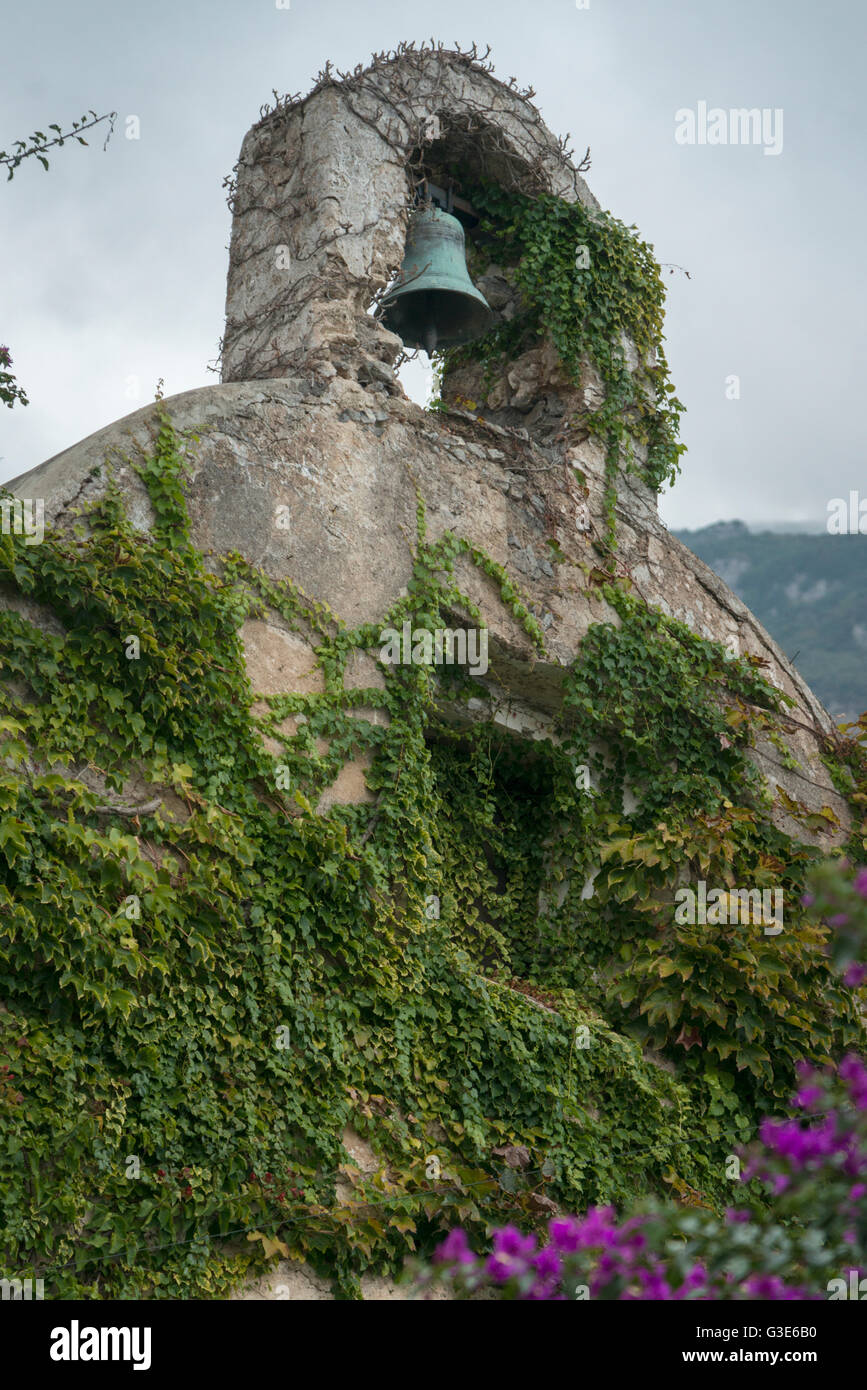 A green bell in a niche over a wall covered in vines; Laurito, Campania, Italy Stock Photo