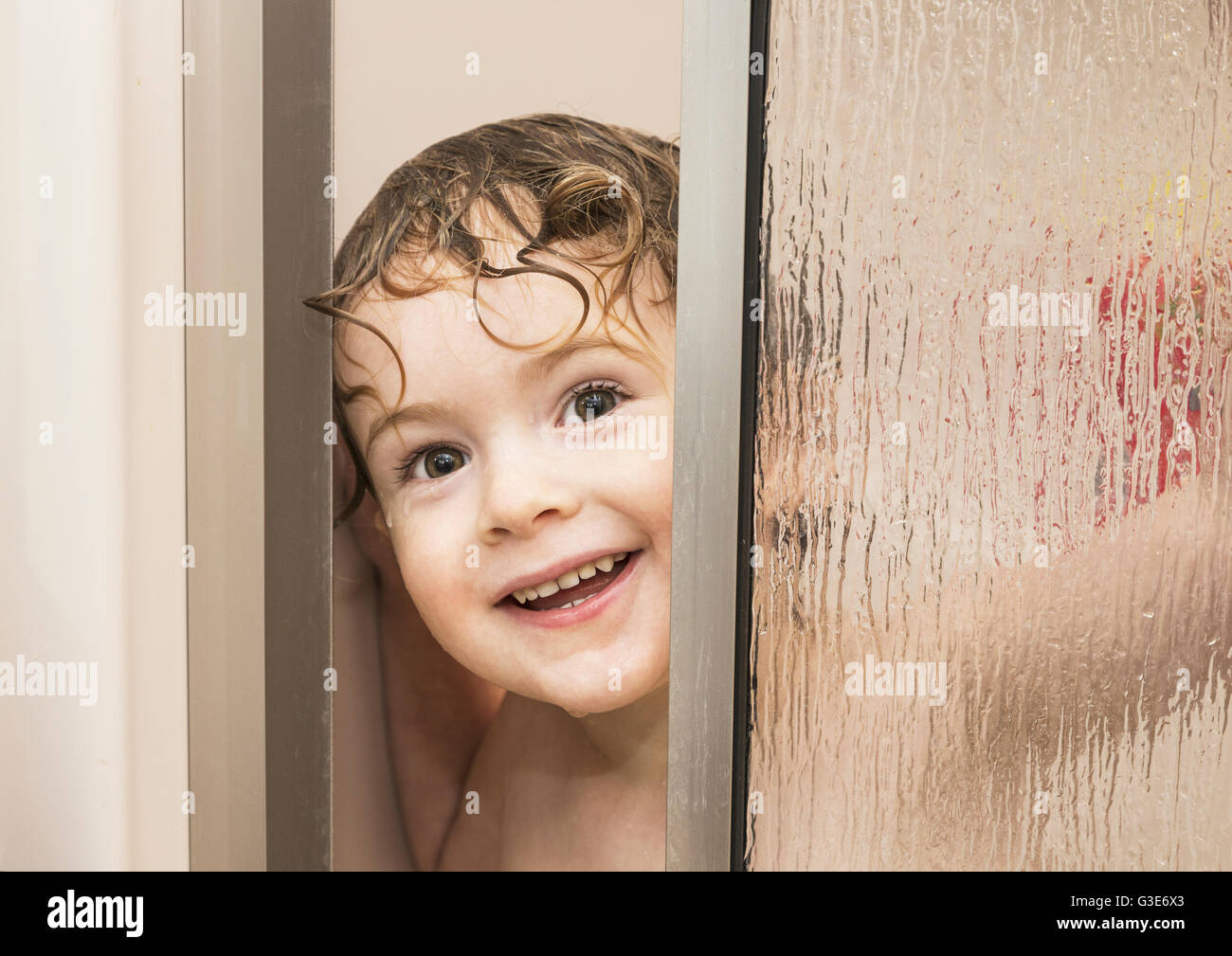 Youngster Smiling And Peeking Out From Behind A Glass Shower Door In A Bathroom St Albert 5220