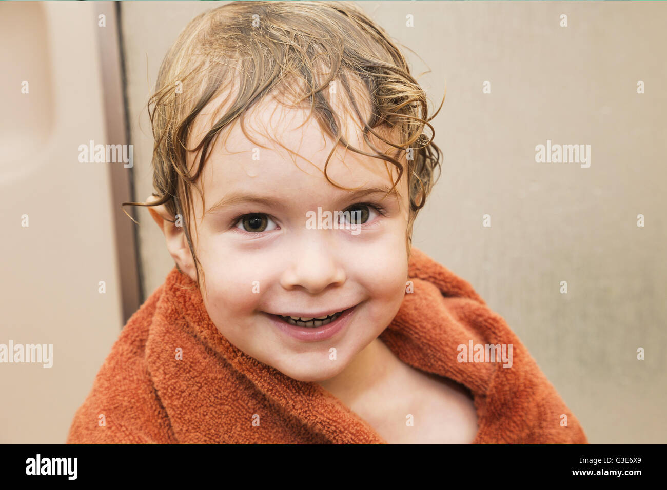 Young boy smiling and getting dry with a towel after having a shower in