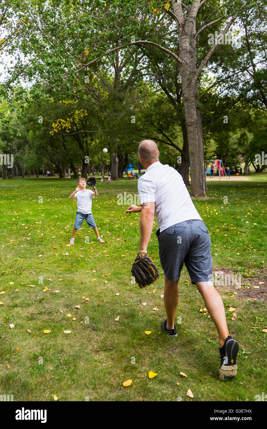 Father and son playing baseball in a park; Edmonton, Alberta, Canada Stock Photo