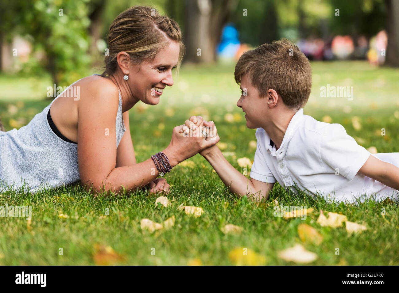 Mother arm wrestling with her son in a park during a family outing