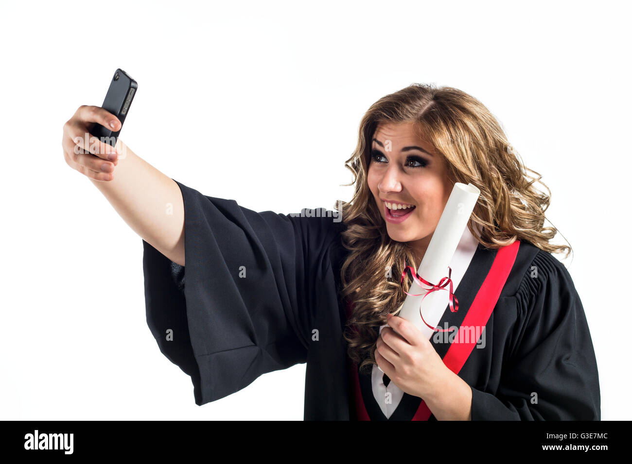 Young graduating woman taking a self-portrait with her smart phone and celebrating her graduation; Edmonton, Alberta, Canada Stock Photo