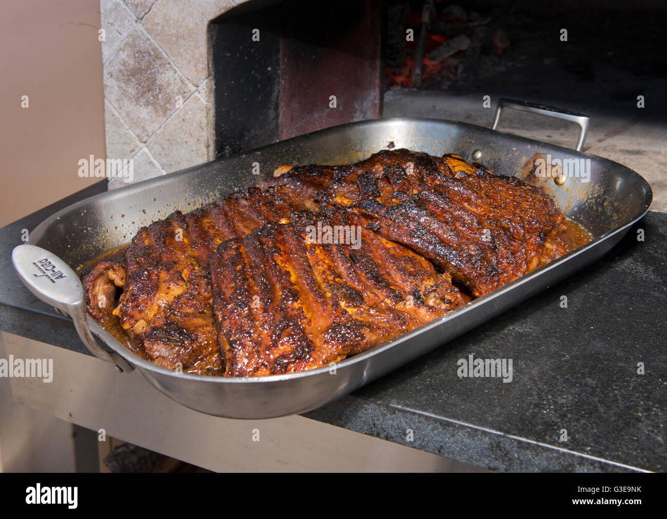 Slow roasted baby back ribs emerge from a wood fired oven. Stock Photo
