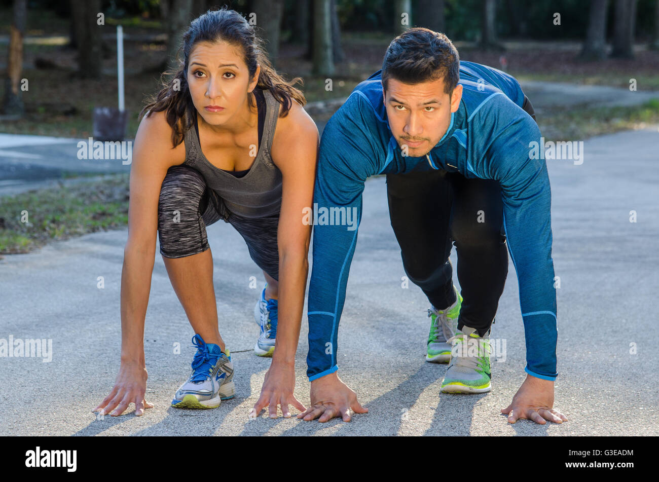 ethnic Hispanic male and female athletes running track Stock Photo