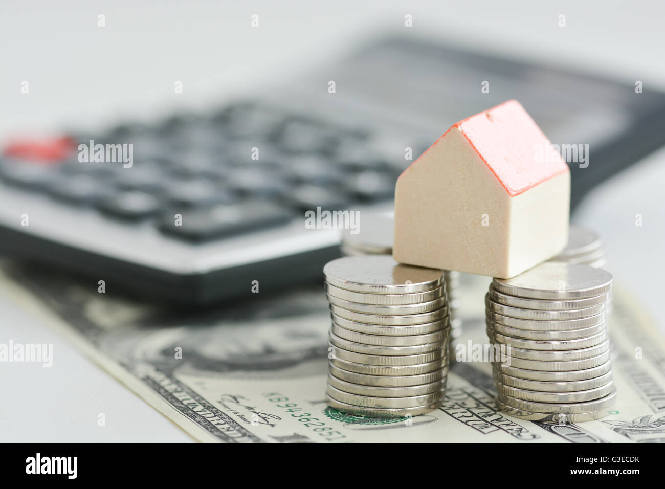 House ownership concept – a model house on a pile of coins Stock Photo