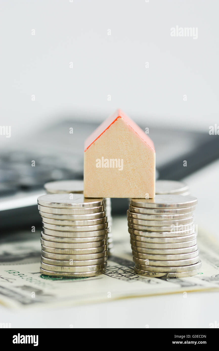 House ownership concept – a model house on a pile of coins Stock Photo