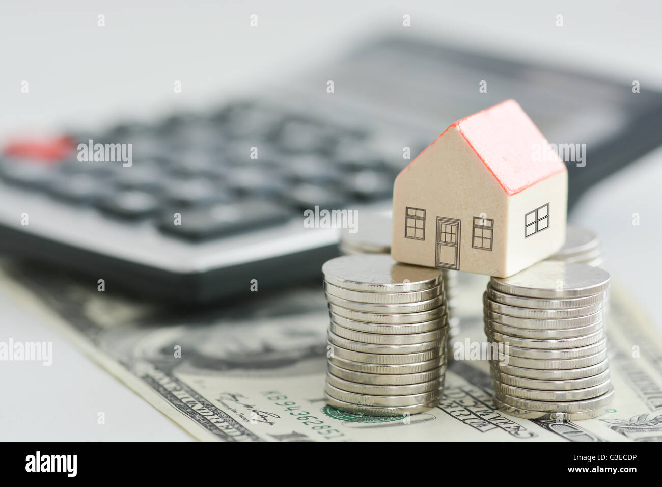 House ownership concept – a model house on a pile of coins Stock Photo