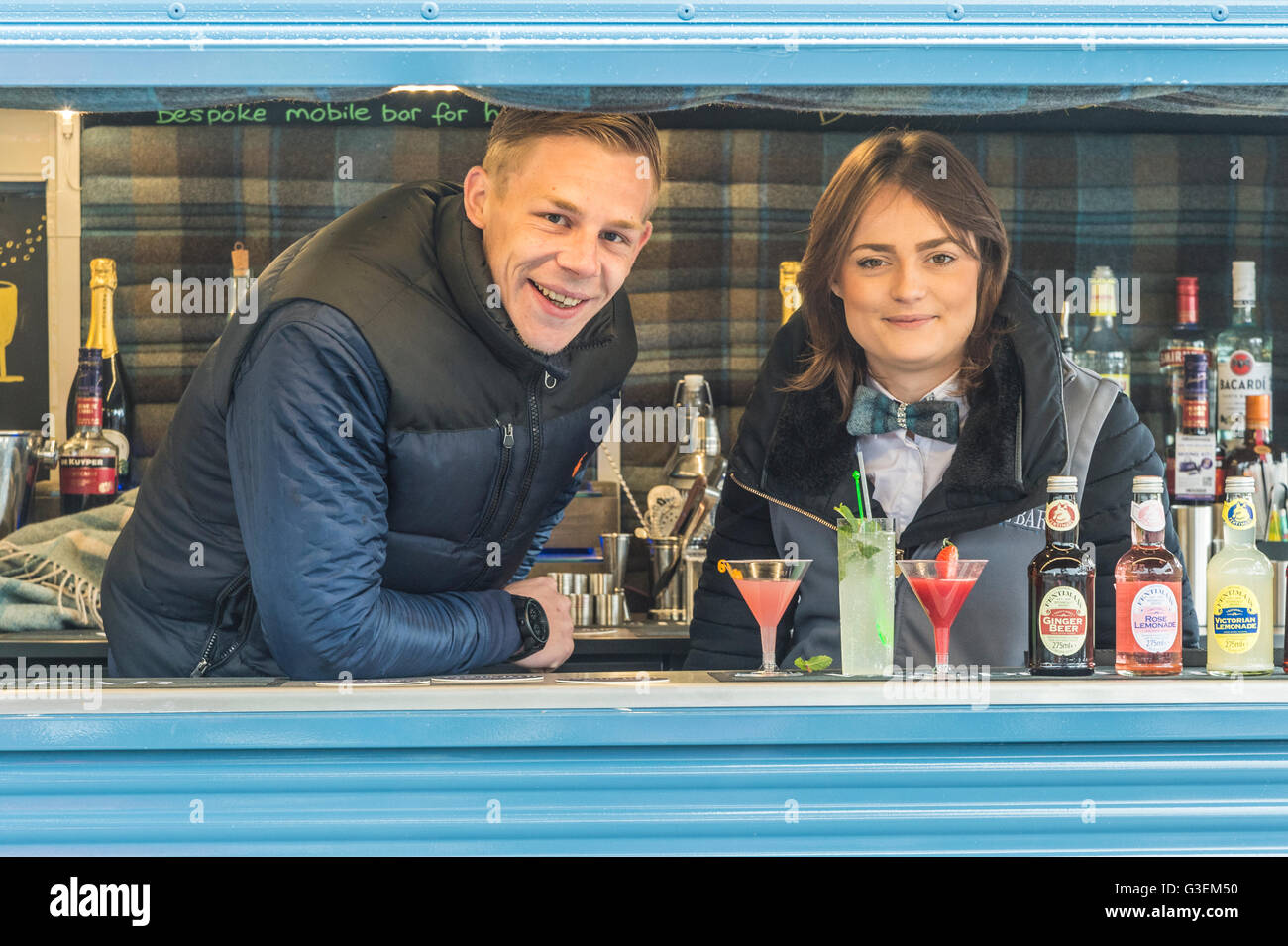Casual outdoor portrait of a happy young couple operating a small business from a 1950's Citroen mobile bar Stock Photo