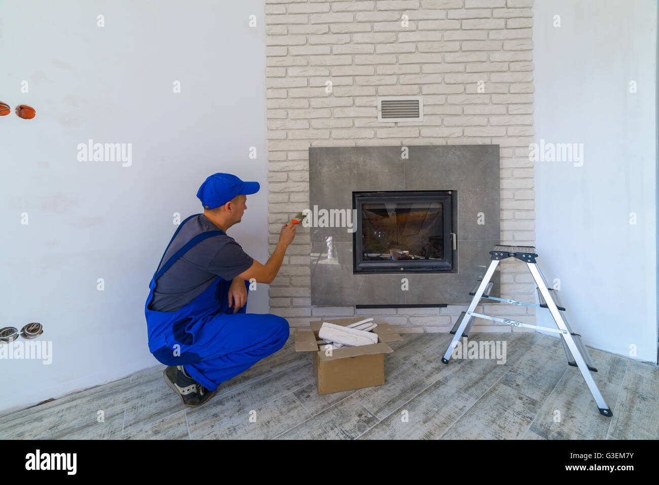 Fireplace installing in white brick wall Stock Photo