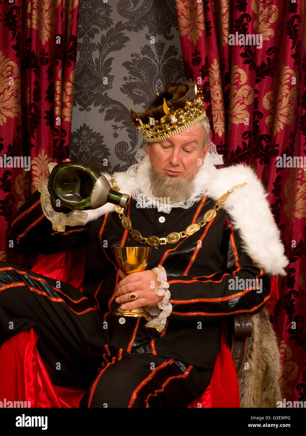 Old funny king getting drunk holding a golden goblet Stock Photo Alamy