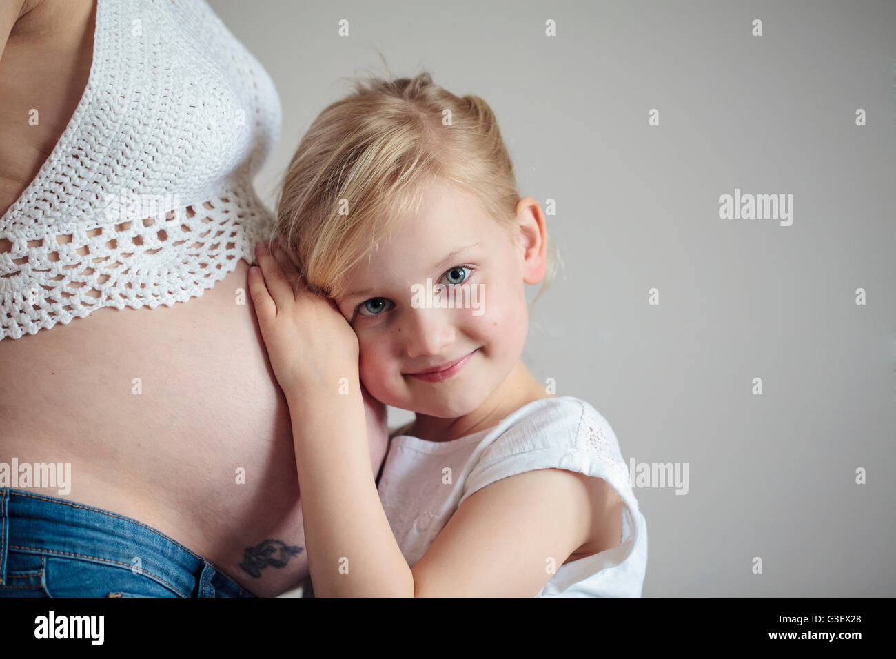 Young girl holding the belly of her pregnant mother Stock Photo