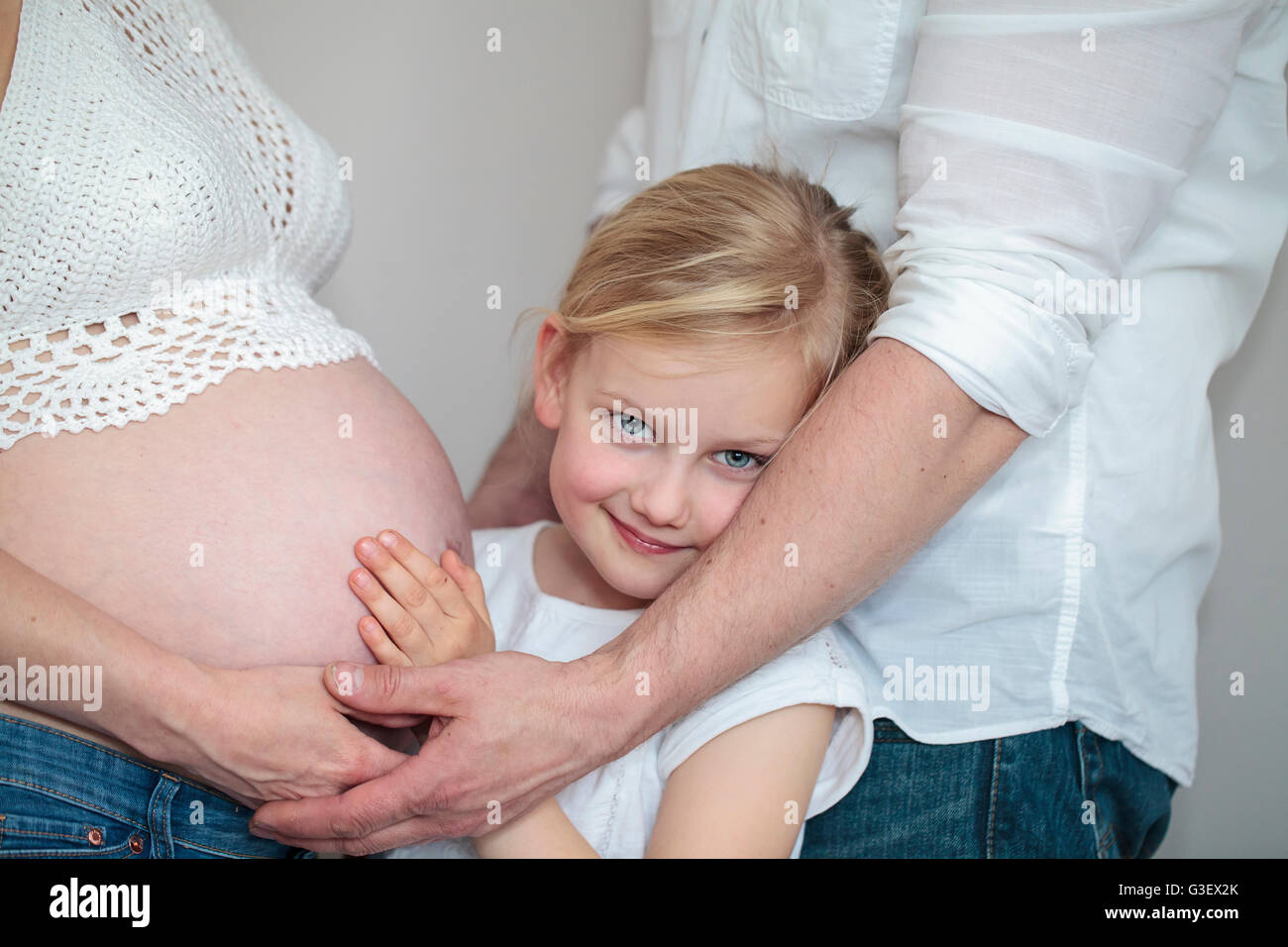 Young girl holding the belly of her pregnant mother Stock Photo