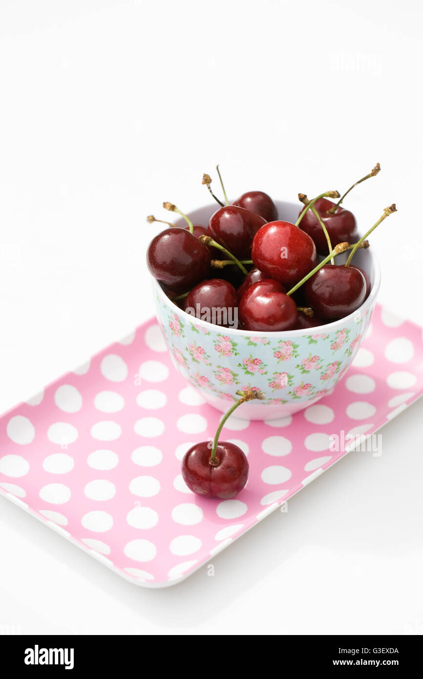Fresh cherries in a bowl on a pink spotty tray. Stock Photo