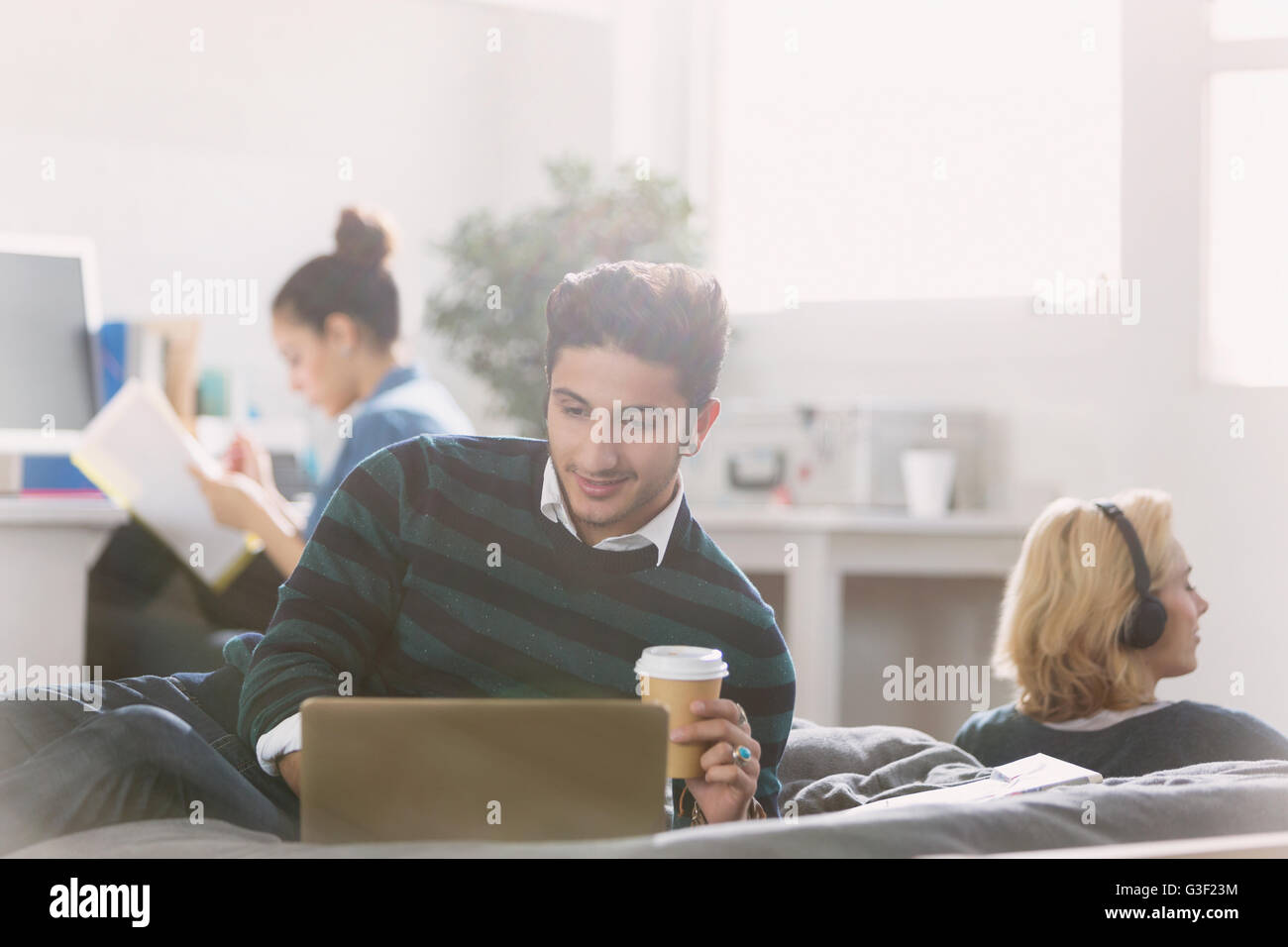 Male college student drinking coffee at laptop Stock Photo Alamy