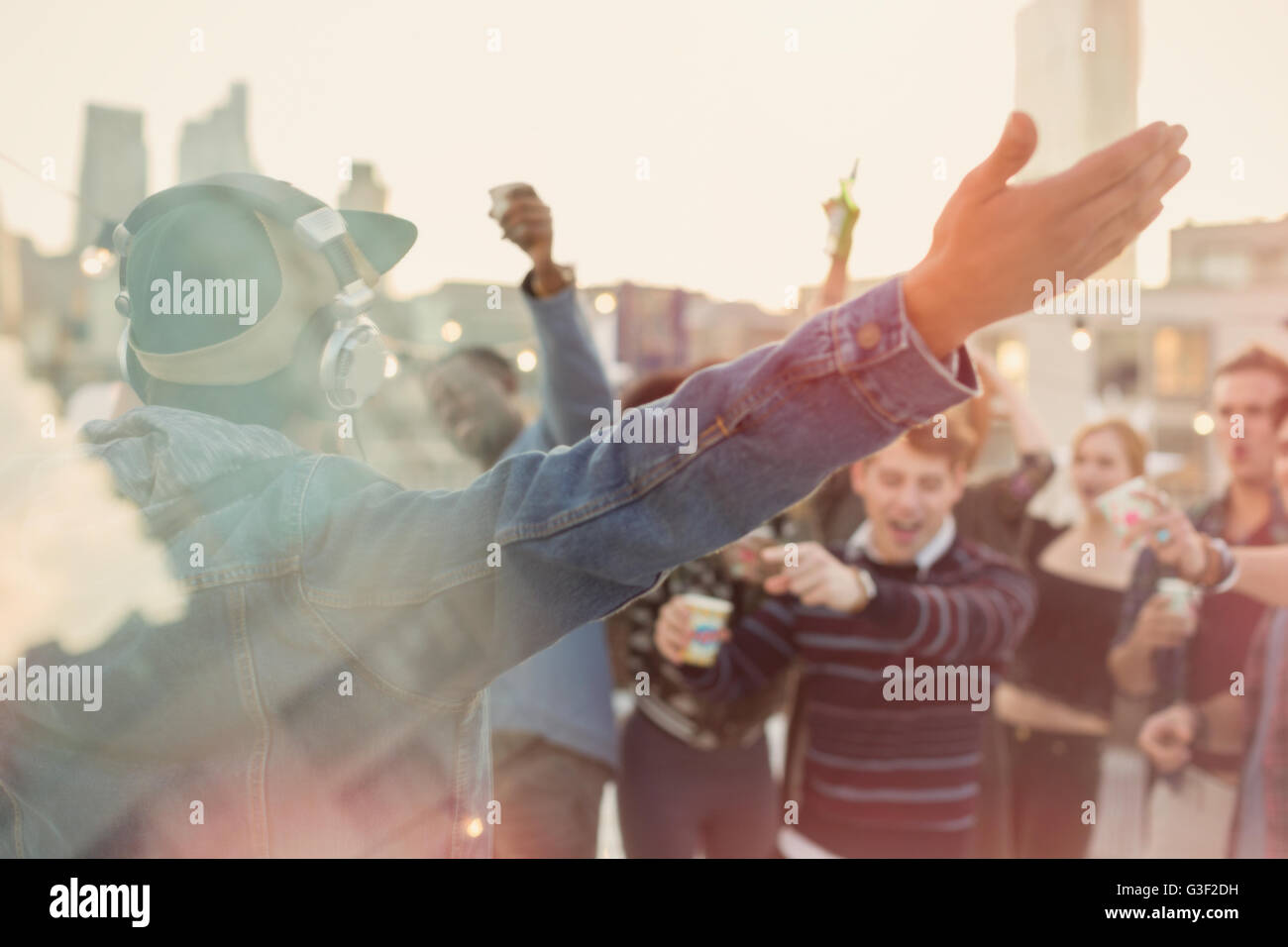 Young adult friends cheering for DJ at rooftop party Stock Photo