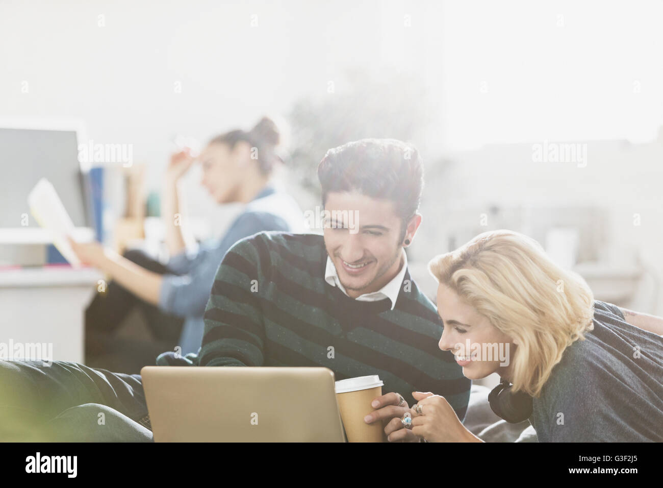 Young couple drinking coffee and using laptop Stock Photo