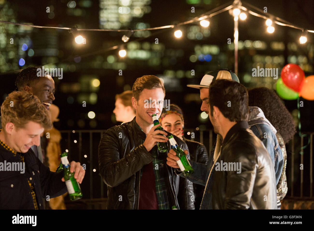 Young men drinking beer at rooftop party Stock Photo