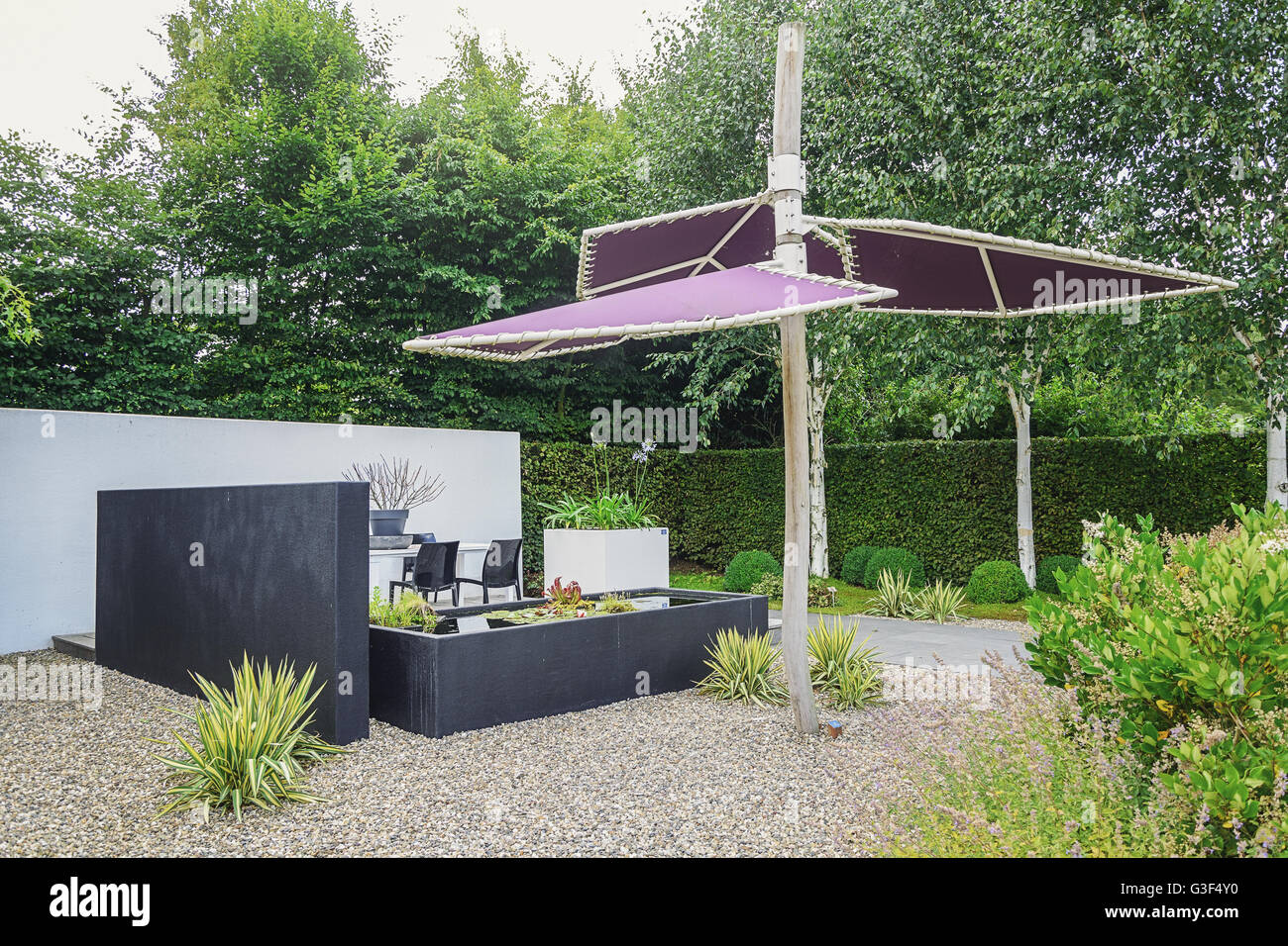 Garden with modern garden furniture,  trendy pond and parasol Stock Photo