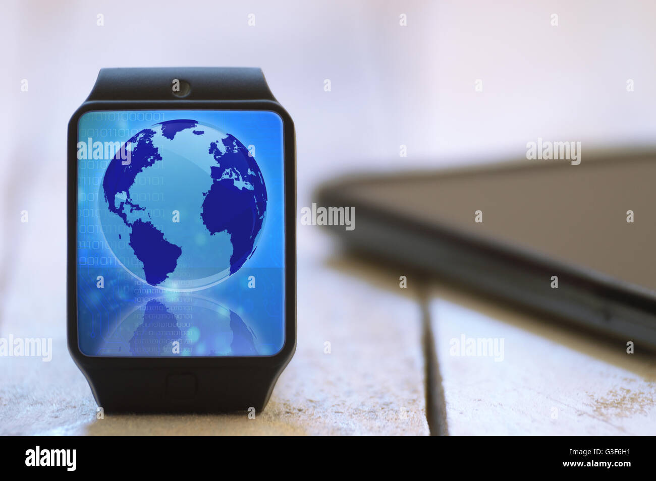 Smart watch on a white wooden table connected to a smart phone. Global communication symbol. Empty copy space for Editor's text. Stock Photo